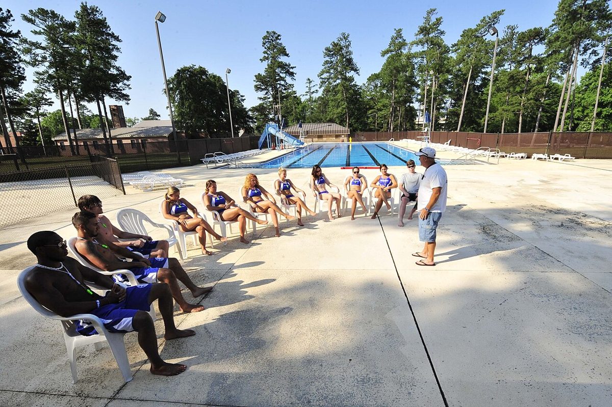 Pool manager leading a lifeguard team briefing on the pool deck