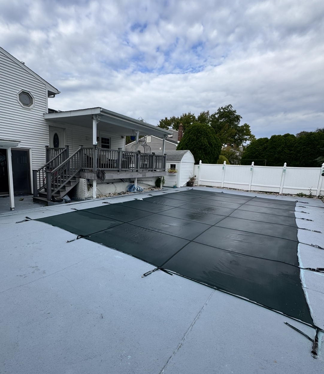 Rectangular residential pool closed for winter under a green safety cover